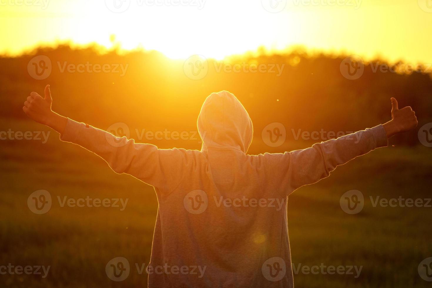 a man in the light of the sunset with his hands up, the concept of success, freedom and joy photo