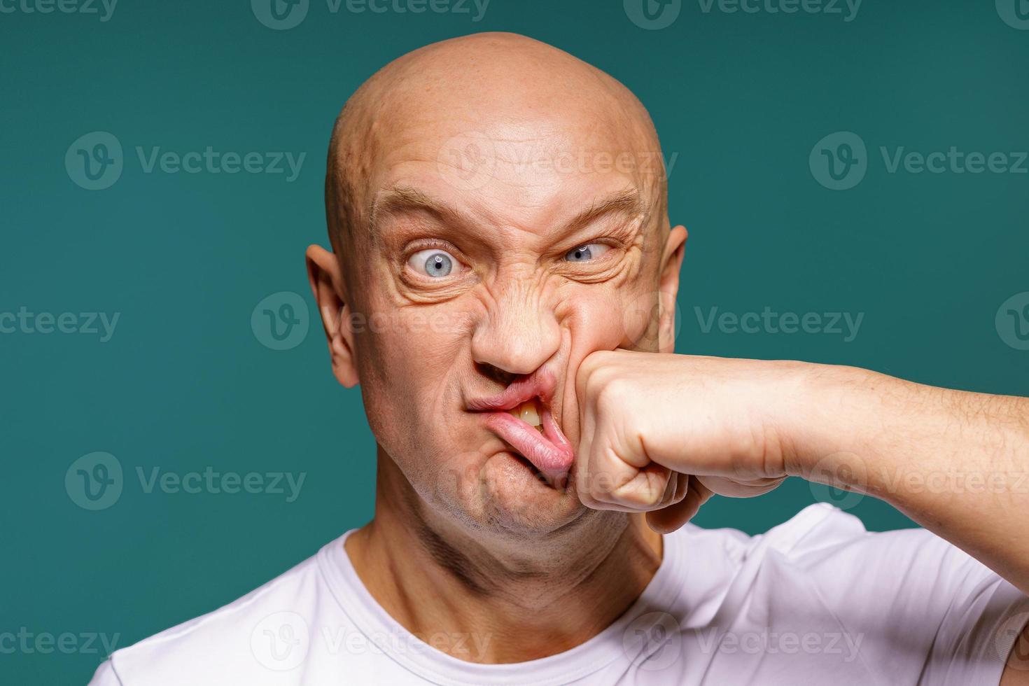 portrait of a bald man punches himself on the cheek, facial expressions photo