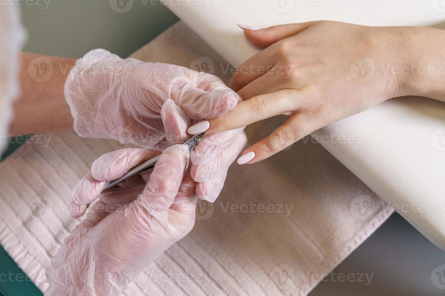 Closeup nail care by manicure specialist in beauty salon. Manicurists clean photo