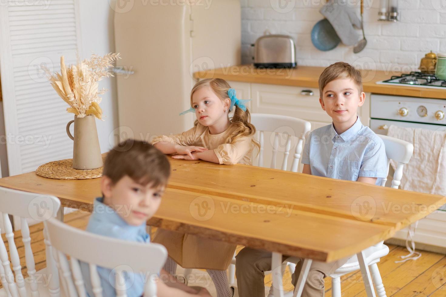 Happy caucasian family with children sitting at kitchen table and drinking photo