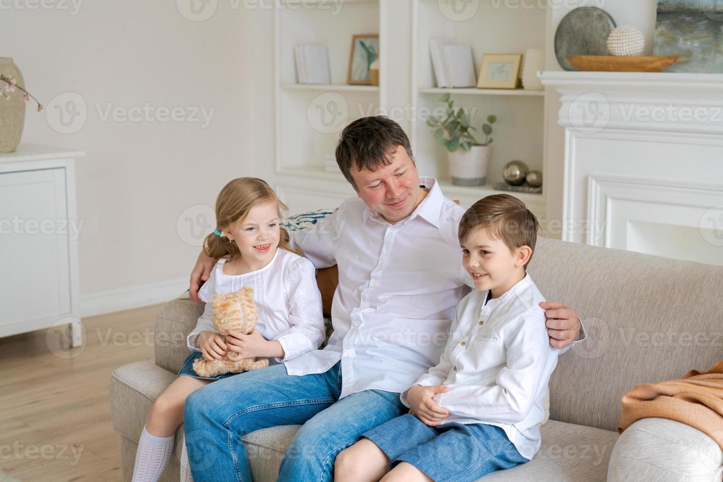 feliz familia caucásica en casa, lindo hijo e hija abrazando a papá, padre foto