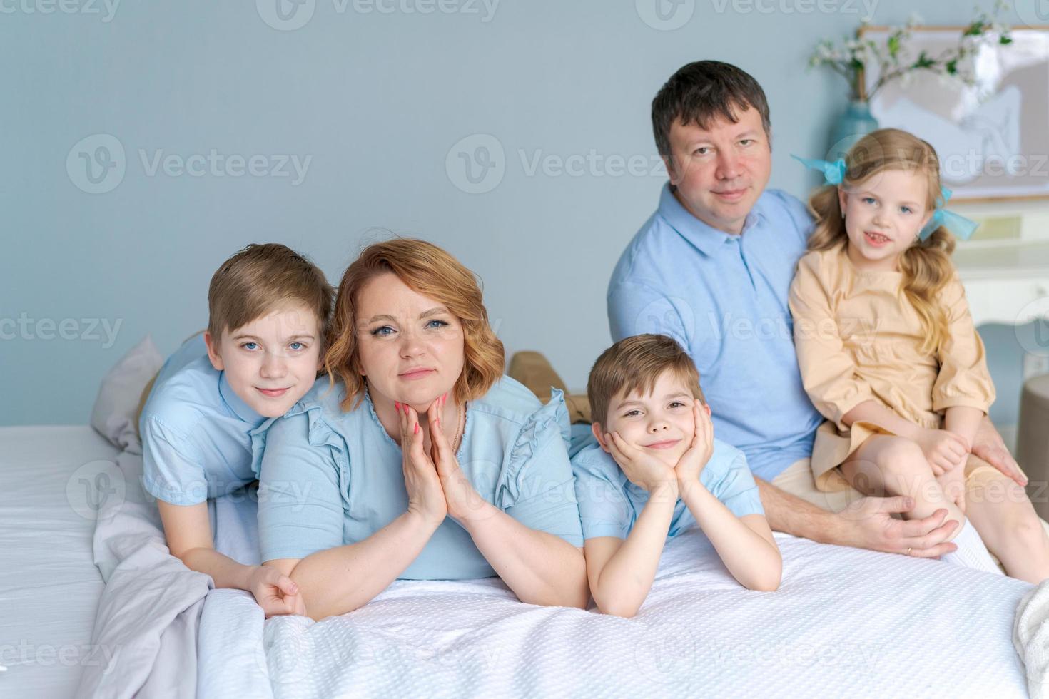 familia feliz mirando la cámara en su cama en el dormitorio. padres caucásicos foto