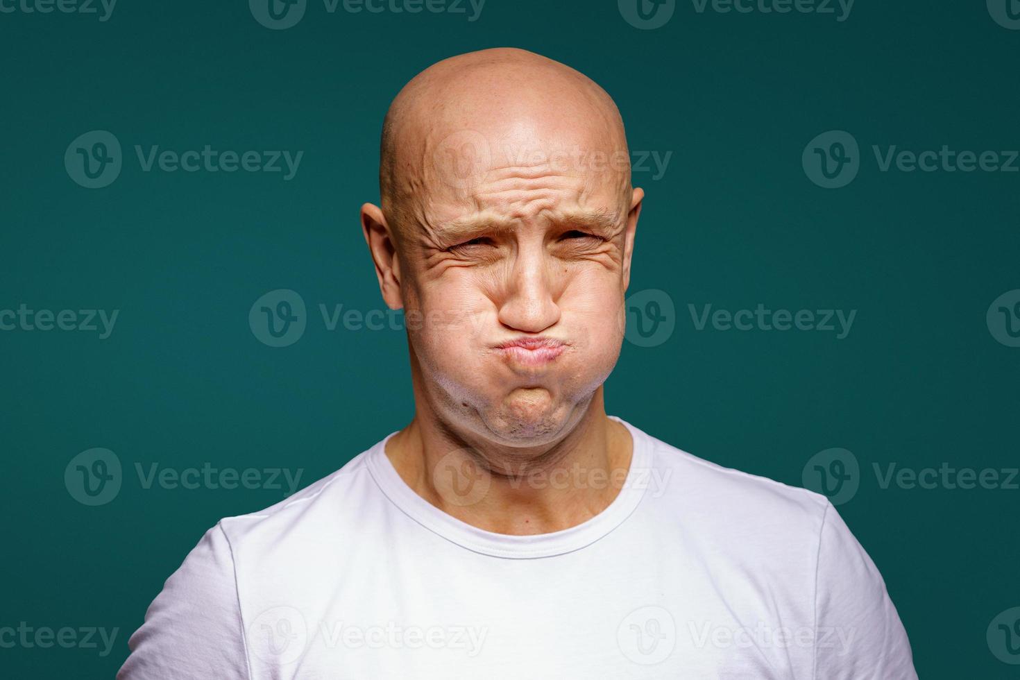 portrait of a bald man puffed out his cheeks on a blue background photo