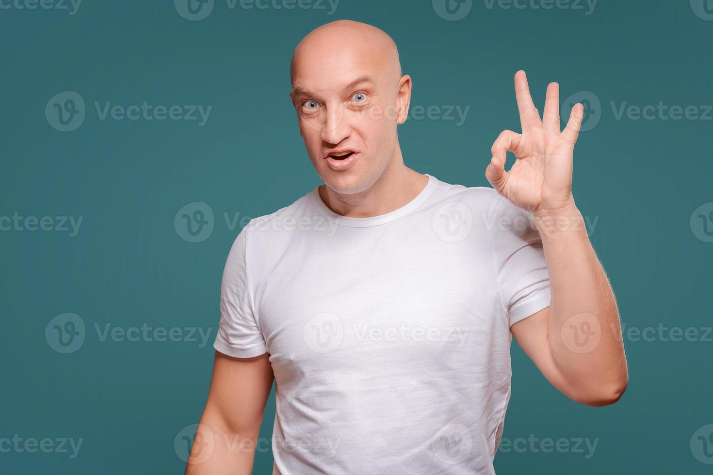 Portrait of a cheerful  man showing okay gesture isolated on the blue background photo