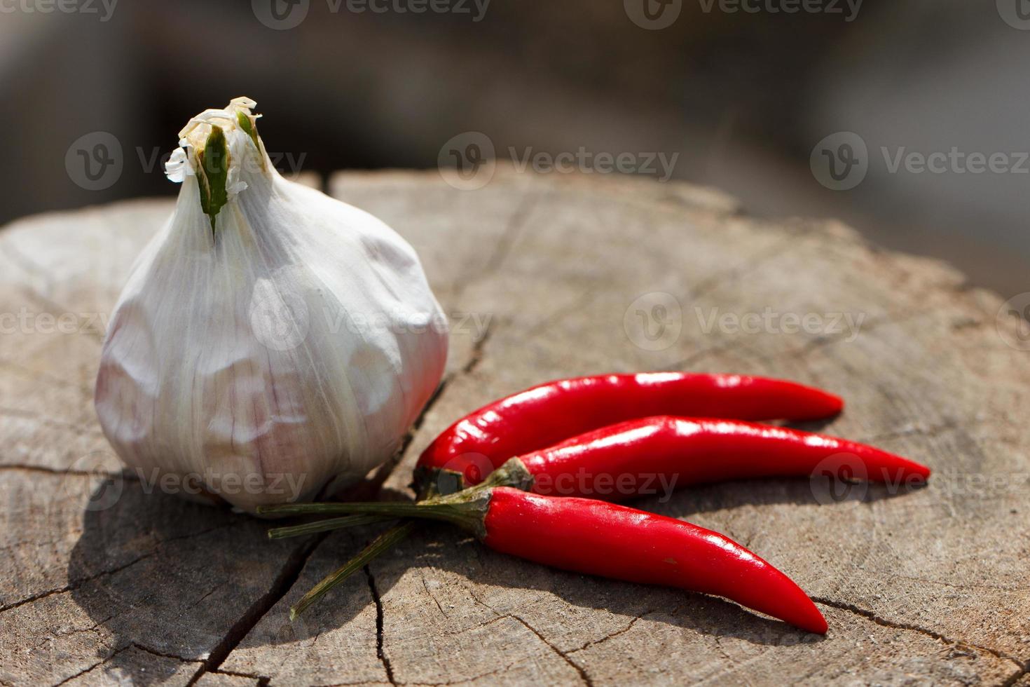 Head of garlic and red hot peppers on a wooden background close-up of a board photo