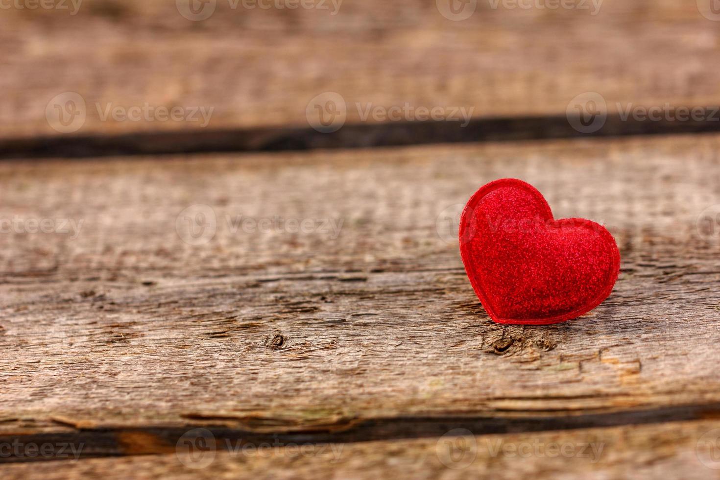 un hermoso corazón rojo yace sobre un fondo de madera foto