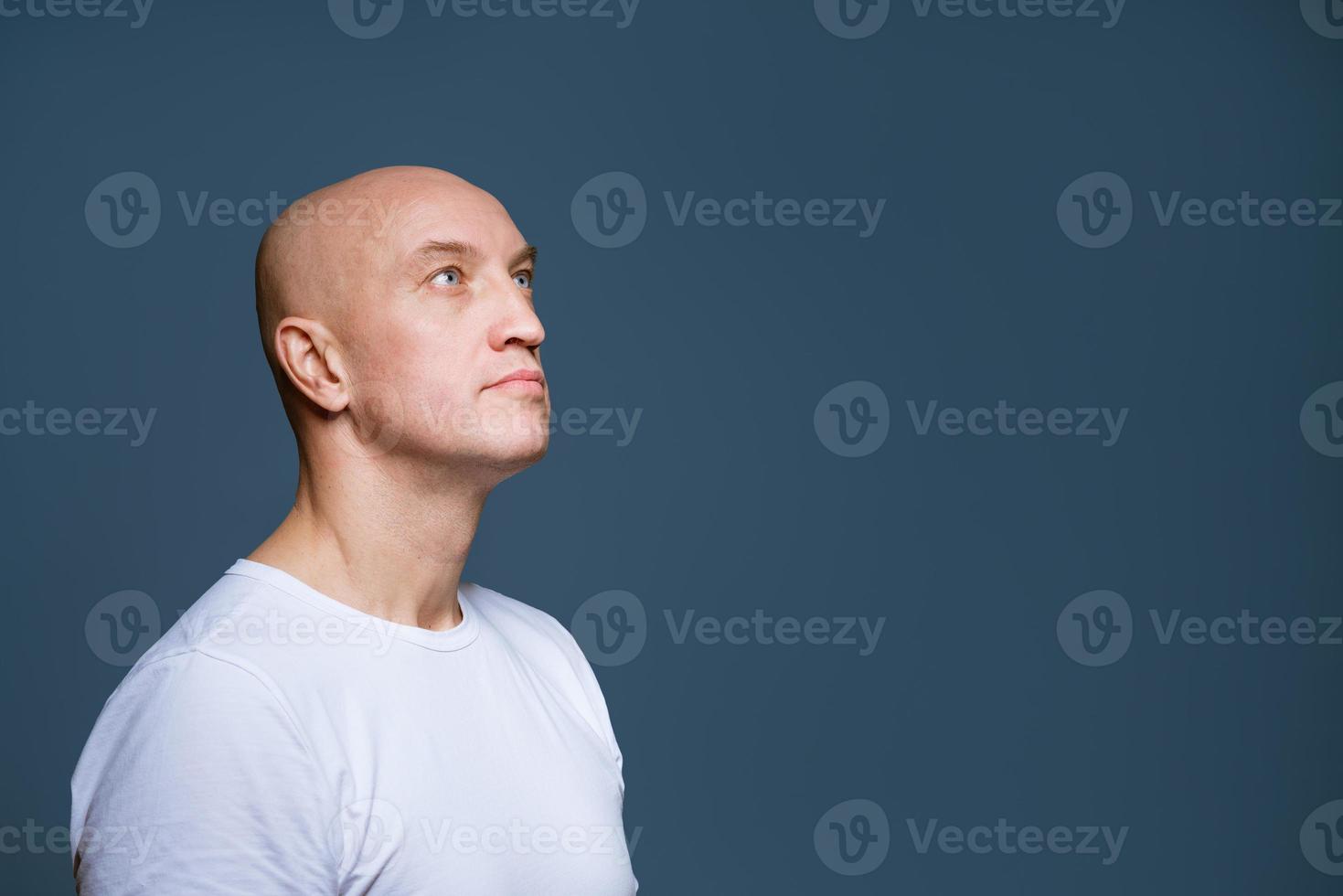 Bald man looking to the side on a blue background photo