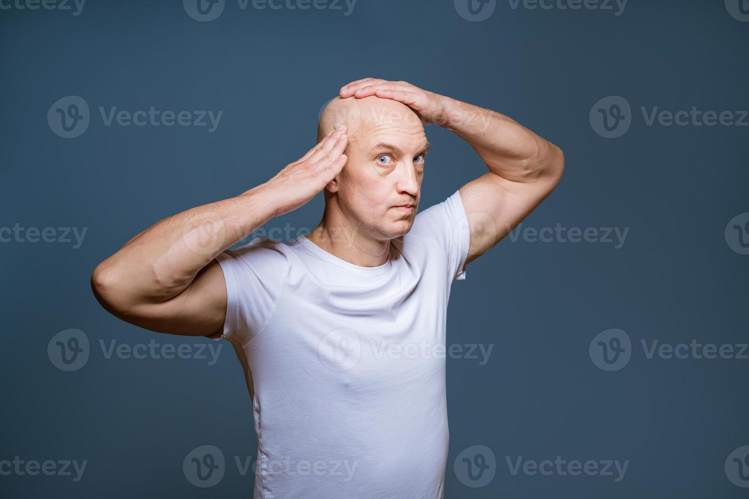 Funny bald man posing on a blue background with excited photo