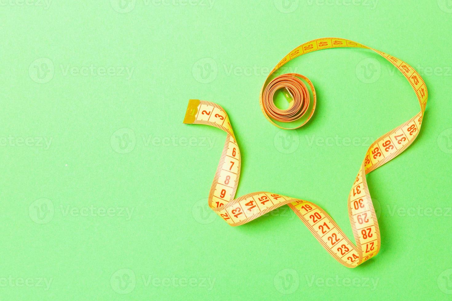 Rolled tape measure with space for your design. Top view of slim waist concept on green background photo