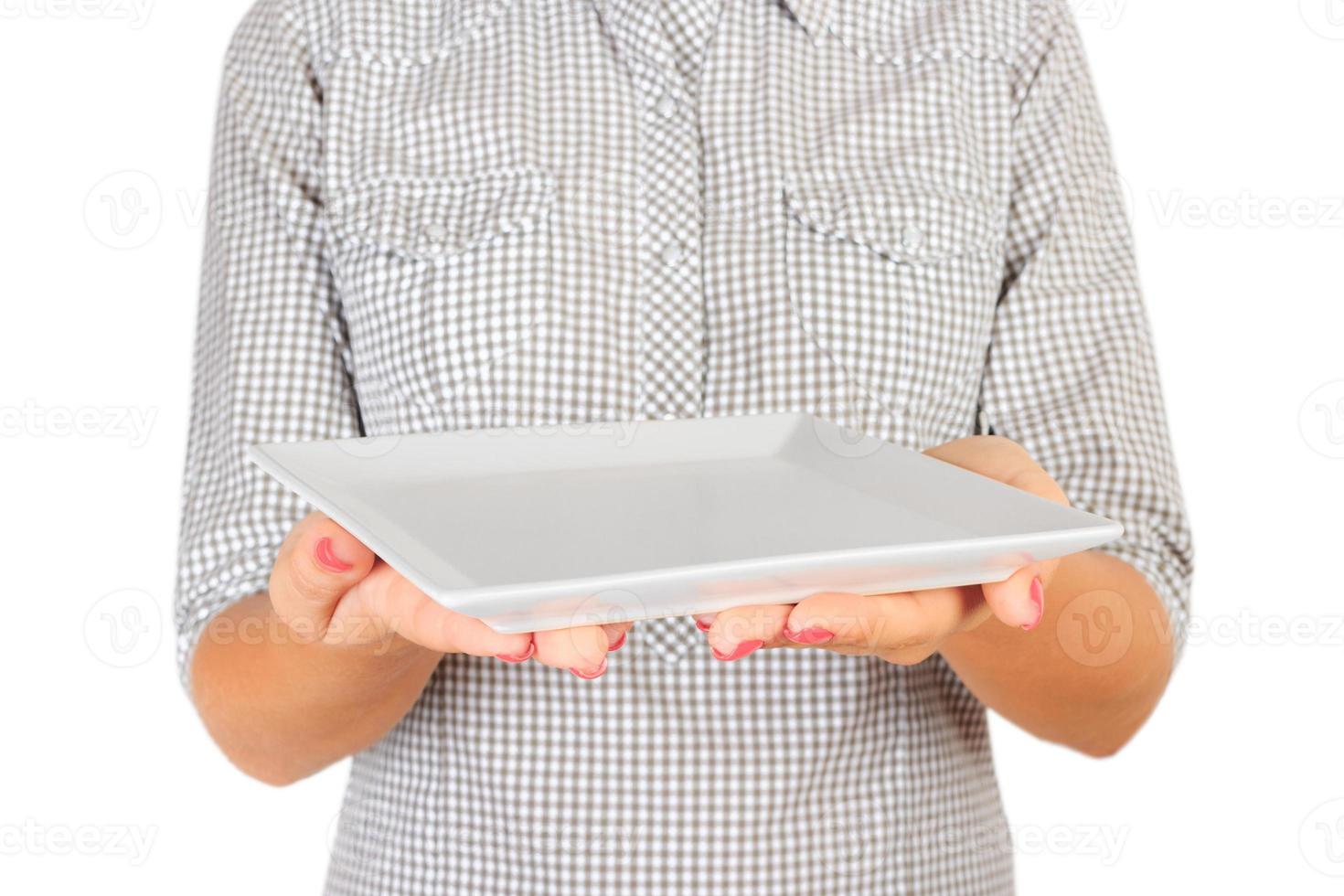 girl in the plaid shirt is holding an empty square matte plate in front of her. woman hand hold empty dish for you desing. perspective view, isolated on white background photo