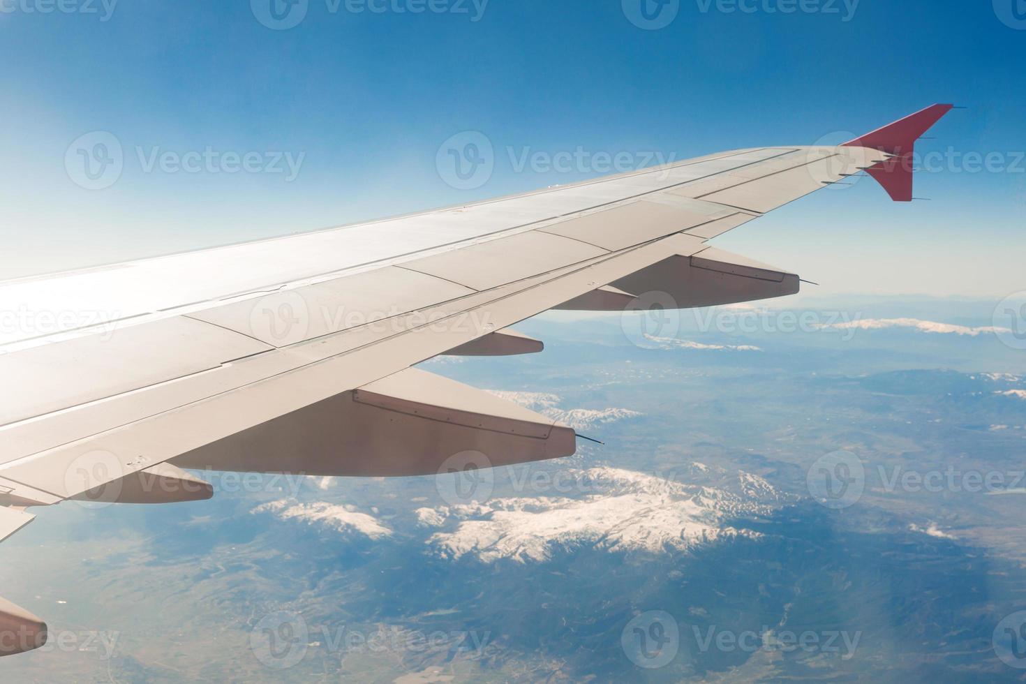 Aircraft wing on the clouds, flies on the mountains background photo