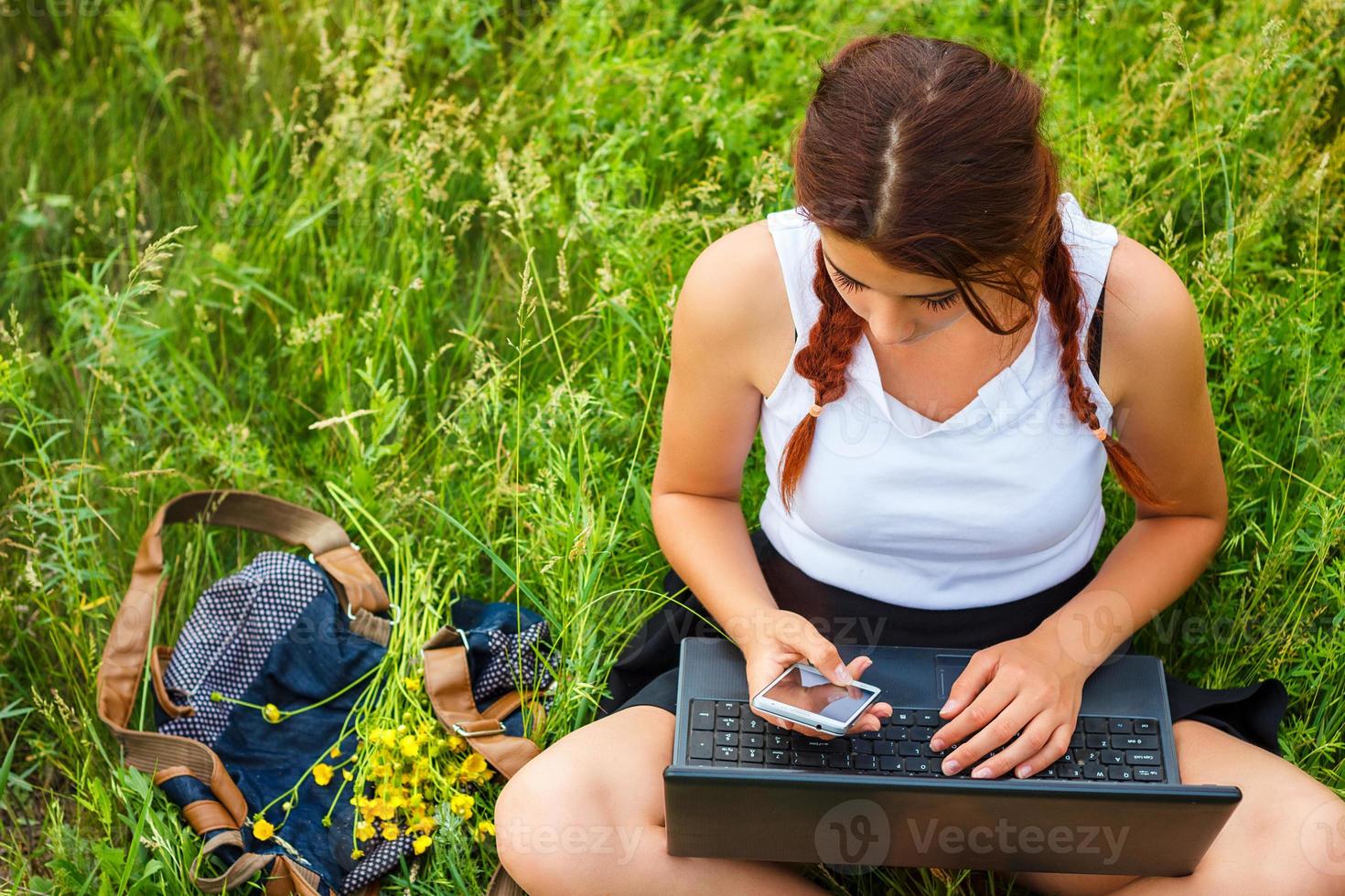 student sitting with a laptop on the grass, top view photo