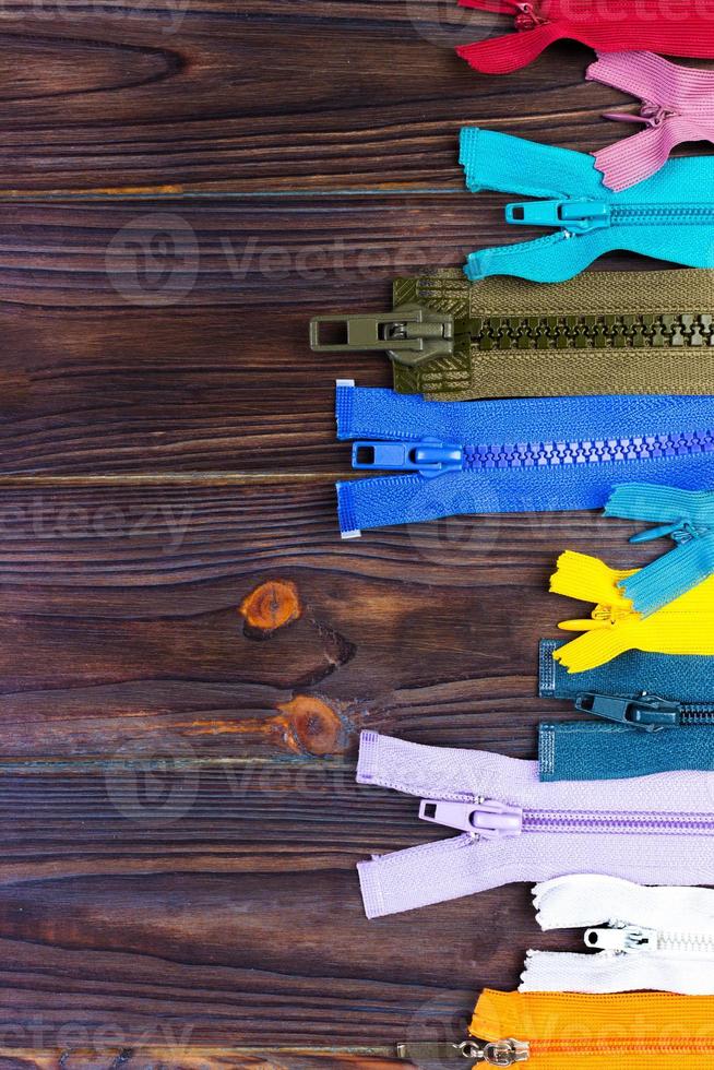 different colorful zippers in front of wood background photo