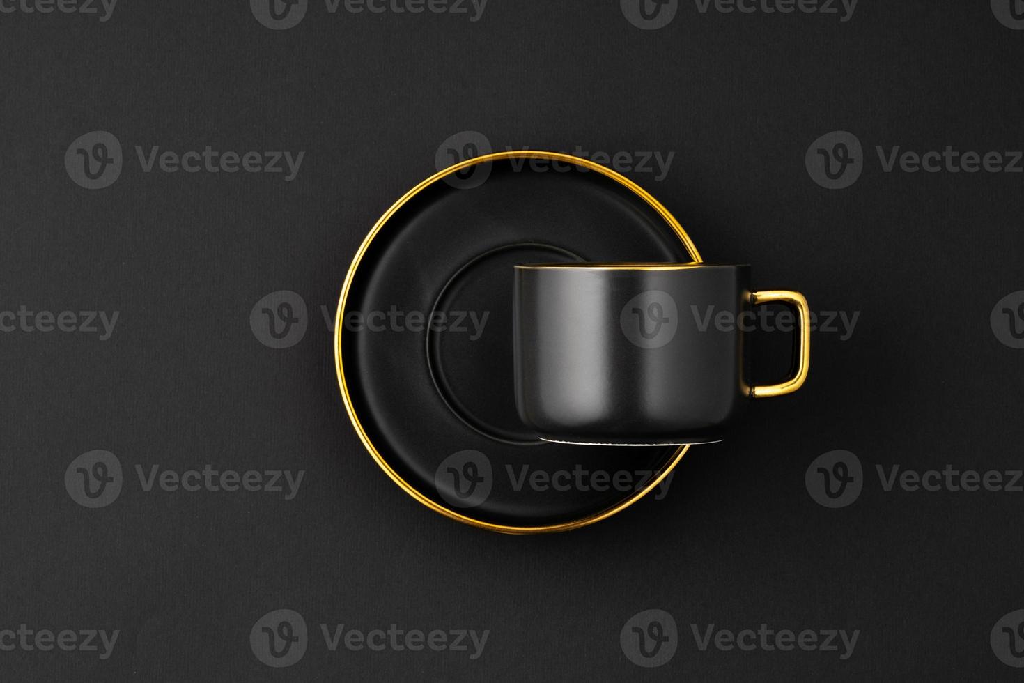 A set of black and golden ceramic plates and cup on a black background. Top view photo