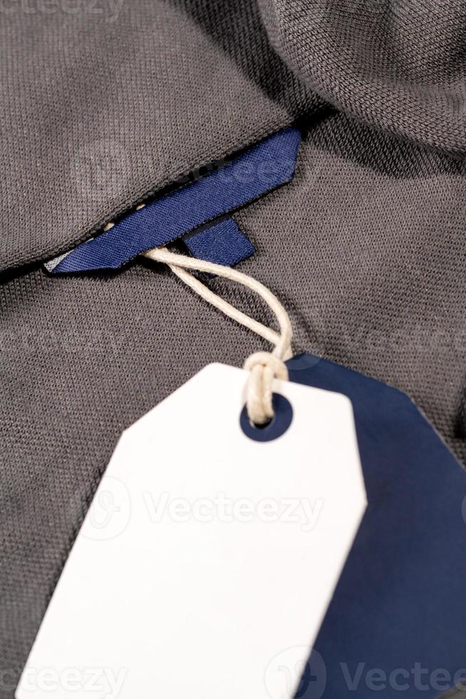 A vertical closeup shot of white blue tags on a string on a cloth with a blank blue tag on the neck photo