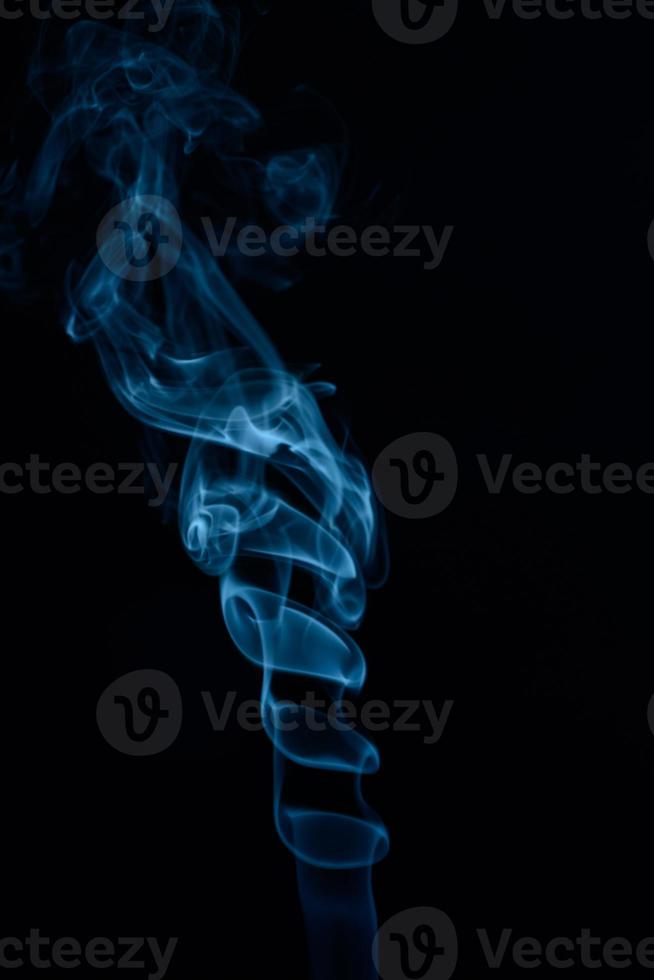 un disparo vertical de humo de tabaco azul sobre un fondo negro foto