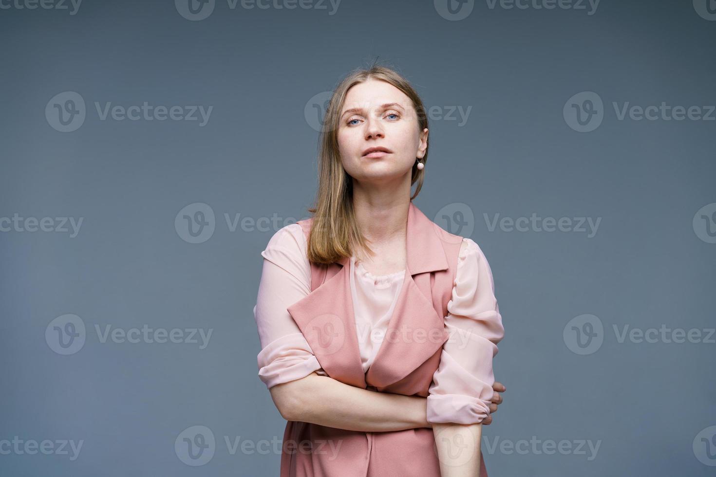 Modest and naive woman with blond hair, stylishly dressed in pink vest photo