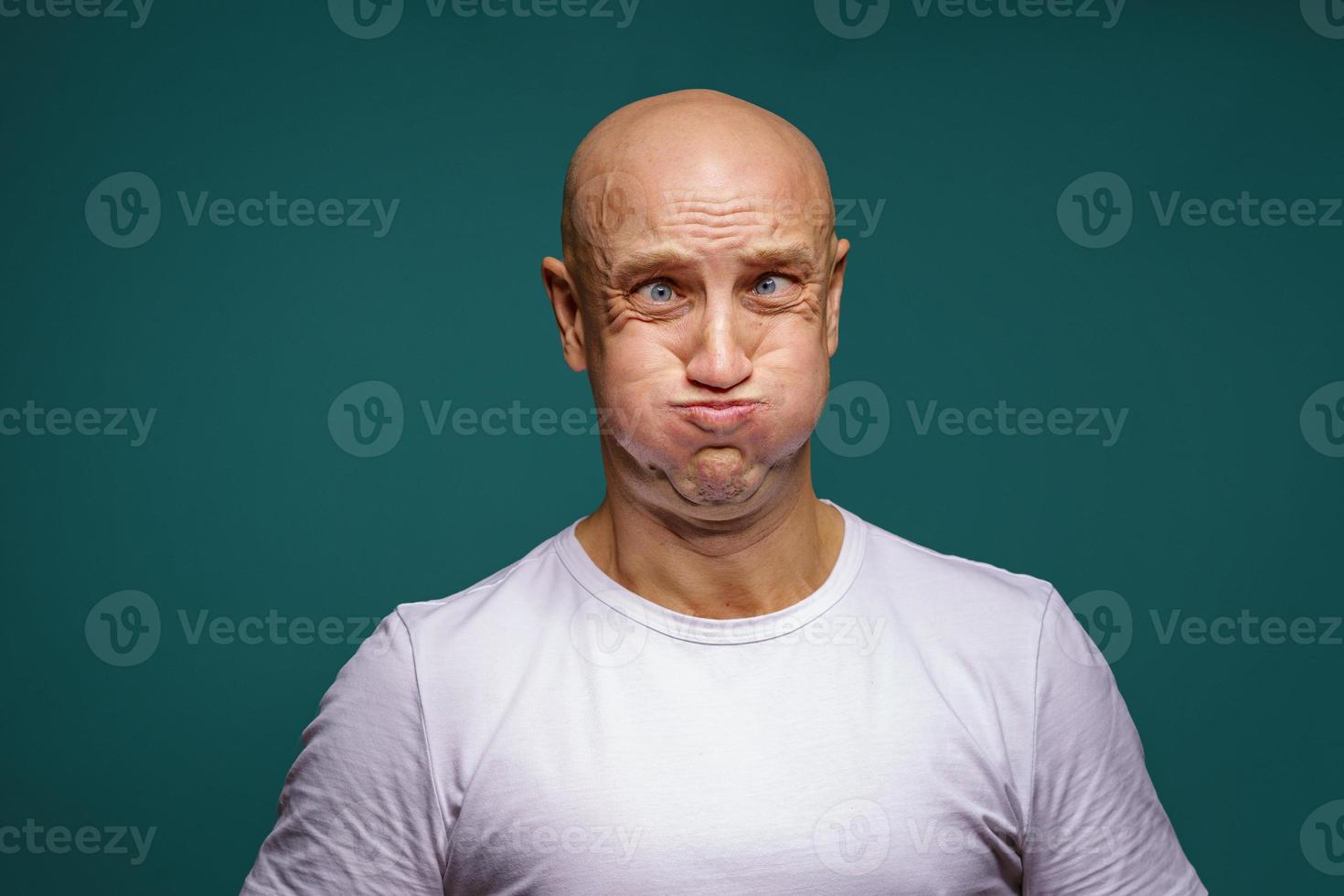 portrait of a bald man puffed out his cheeks on a blue background photo