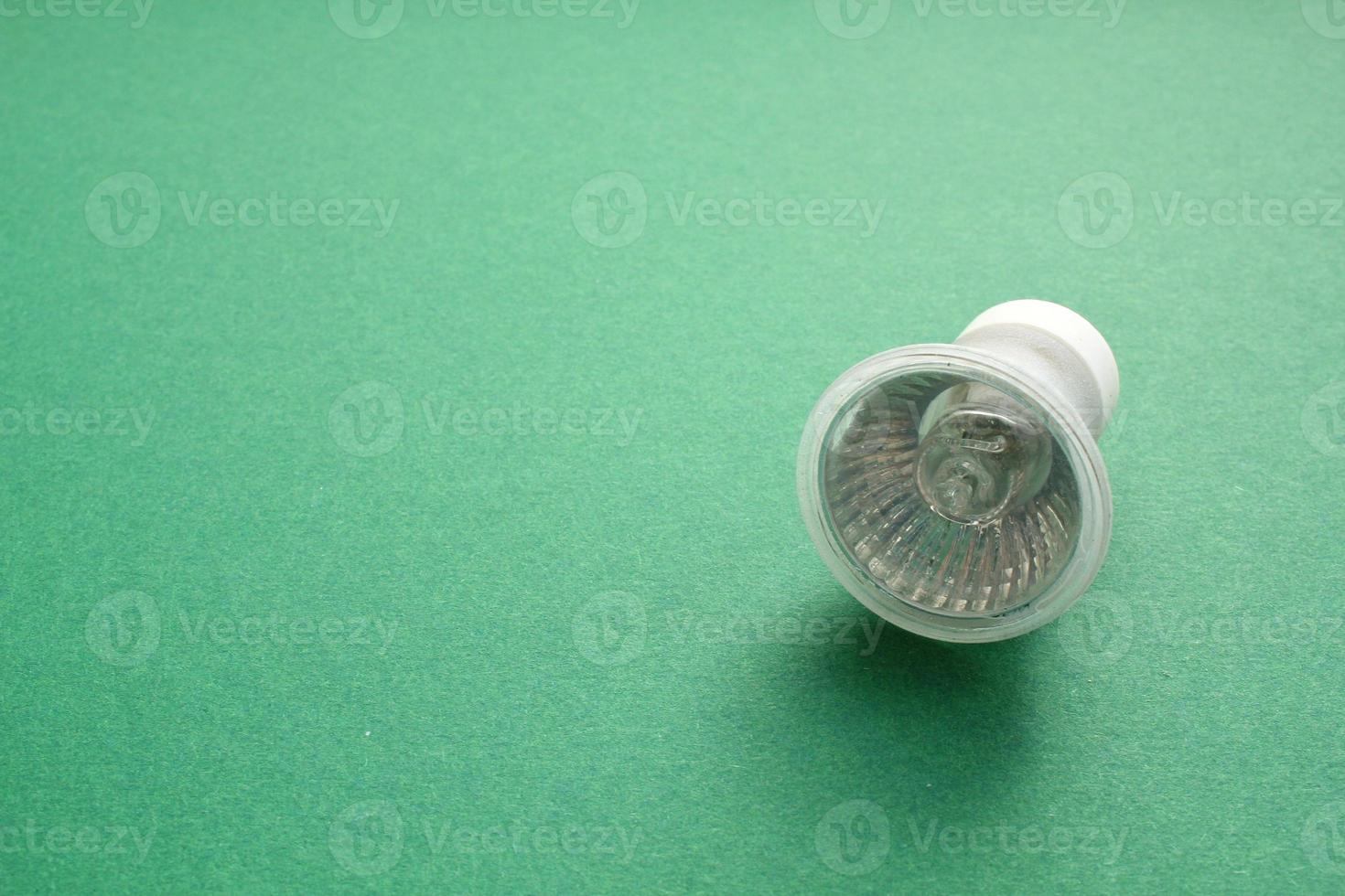 Electric LED light bulb lamp on green background with copy space. Eco saving power and environmental conservation energy efficiency concept. Ecological friendly and sustainable lifestyle. Flat lay photo