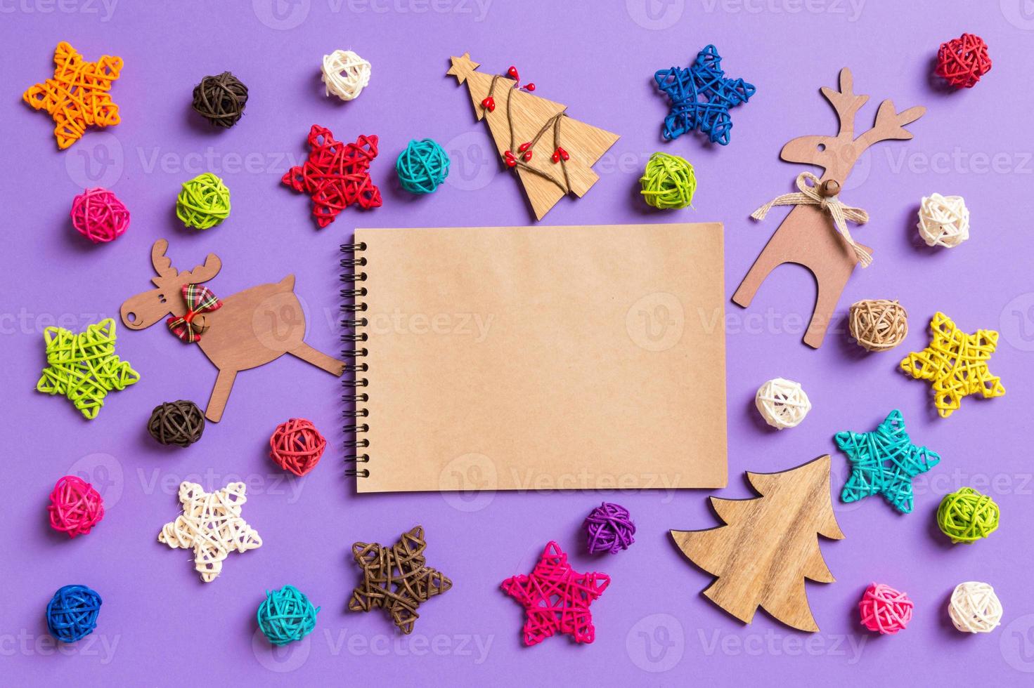 vista superior del cuaderno. decoraciones de año nuevo sobre fondo morado. estrellas festivas y bolas. concepto de feliz navidad foto