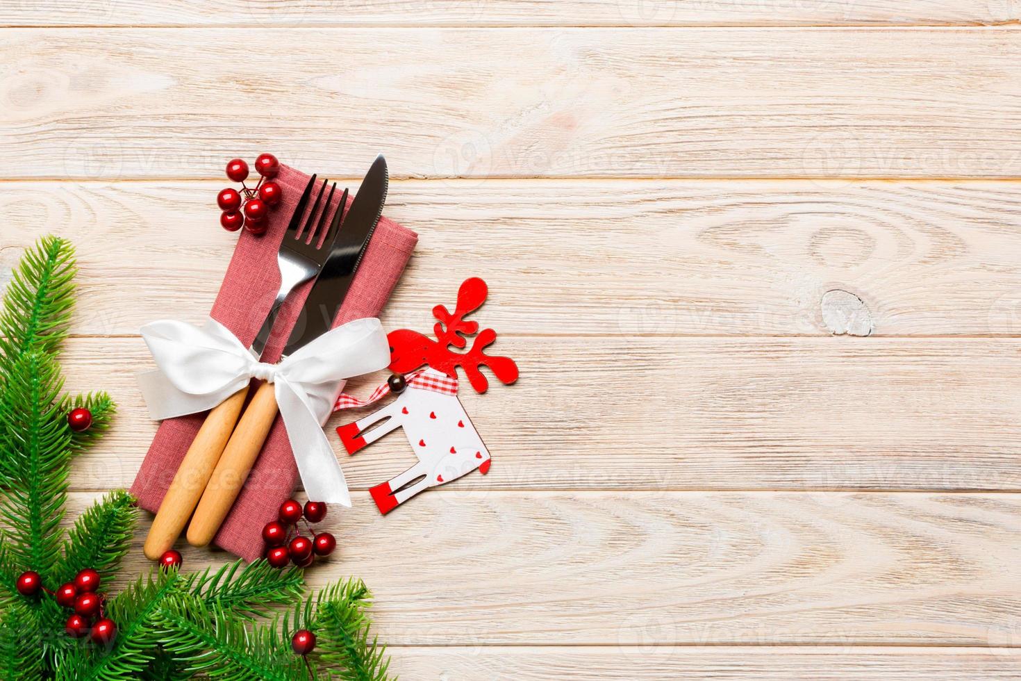 Top view of flatware tied up with ribbon on napkin on wooden background. Christmas decorations and reindeer with empty space for your design. New Year holiday concept photo