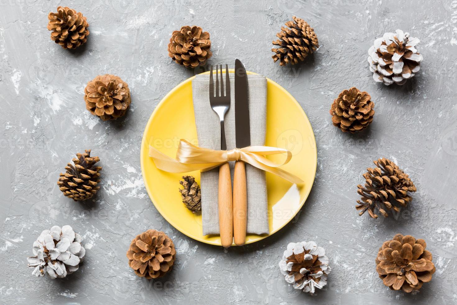 New Year set of plate and utensil on cement background. Top view of holiday dinner decorated with pine cones. Christmas time concept photo