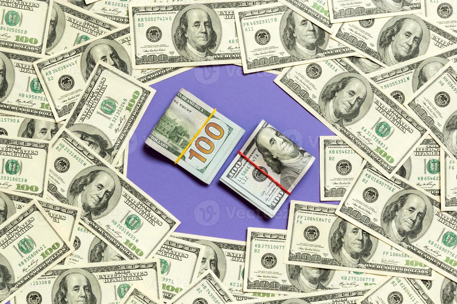 Frame of one hundred dollar bills with stack of money in the middle. Top view of business concept on purple background with copy space photo