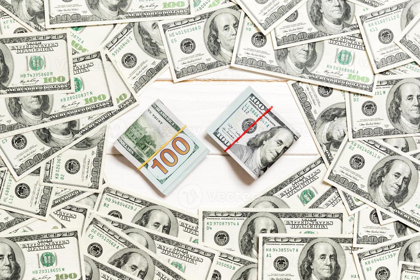 Frame of one hundred dollar bills with stack of money in the middle. Top view of business concept on white wooden background with copy space photo