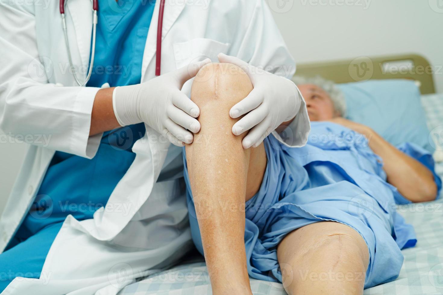 Doctor checking Asian elderly woman patient with scar knee replacement surgery in hospital. photo