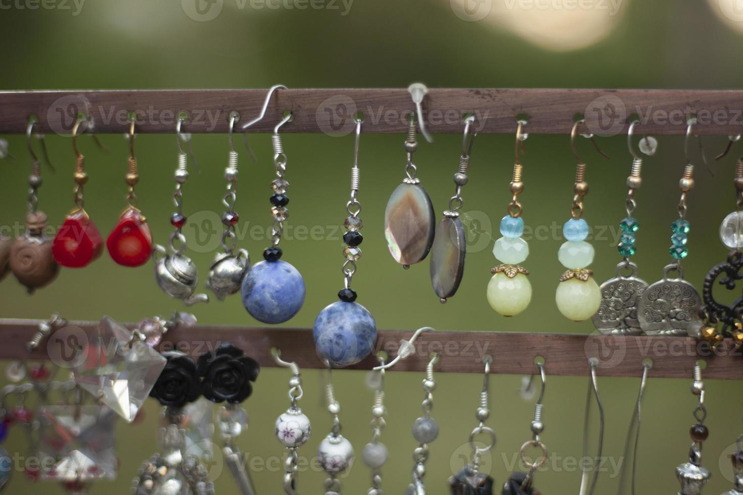 Women's earrings are sold on street. Decoration for girl in shop window. Homemade earrings. photo