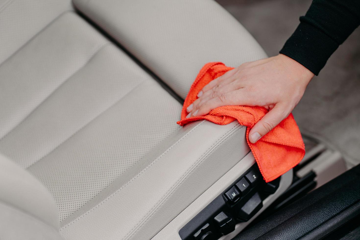 Primer plano de toallitas de mano de hombre asiento de coche con paño de microfibra. concepto de limpieza automática. salón de lavado. limpiando el polvo foto