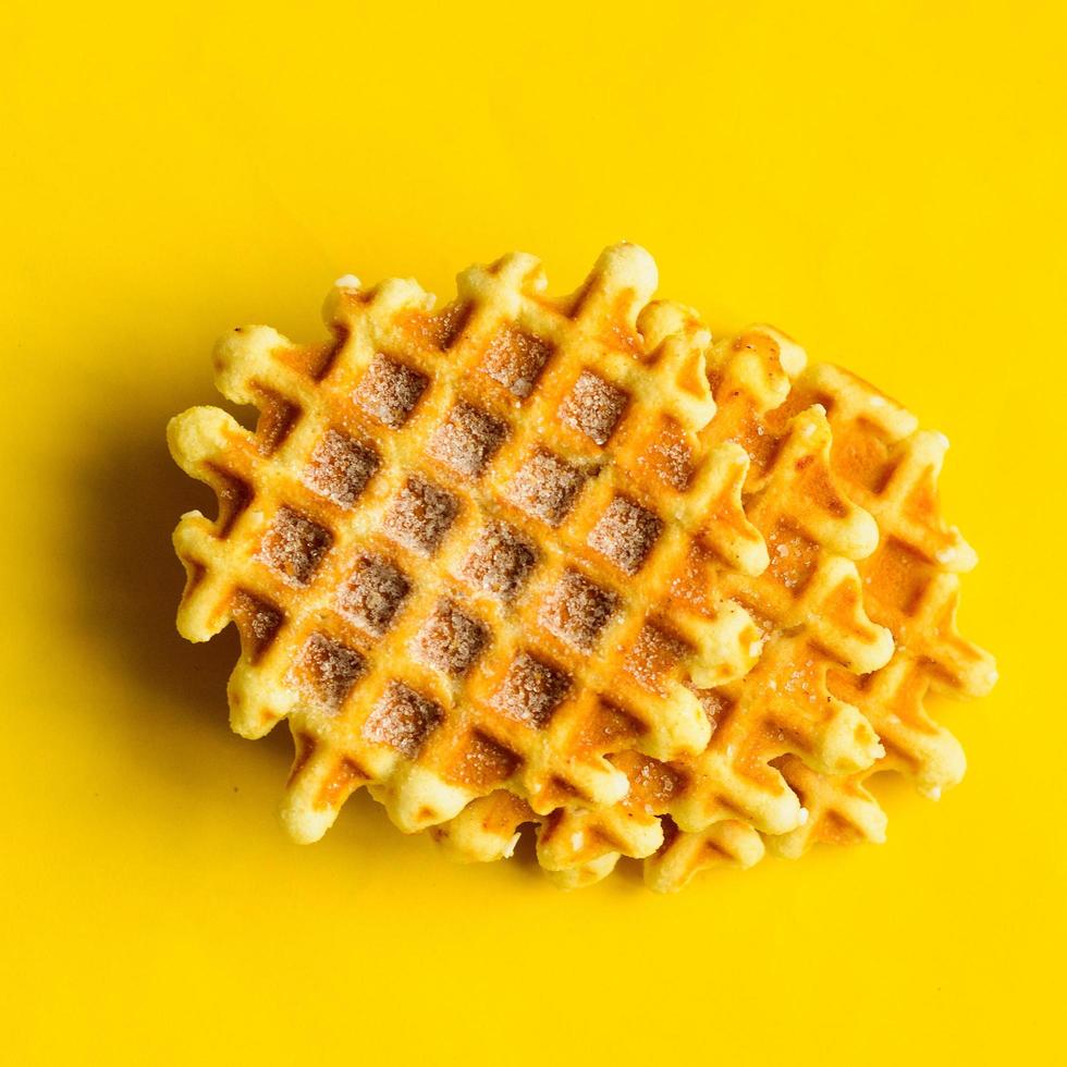 Top view, three sugar belgium waffles on yellow background.Sweet dessert. photo