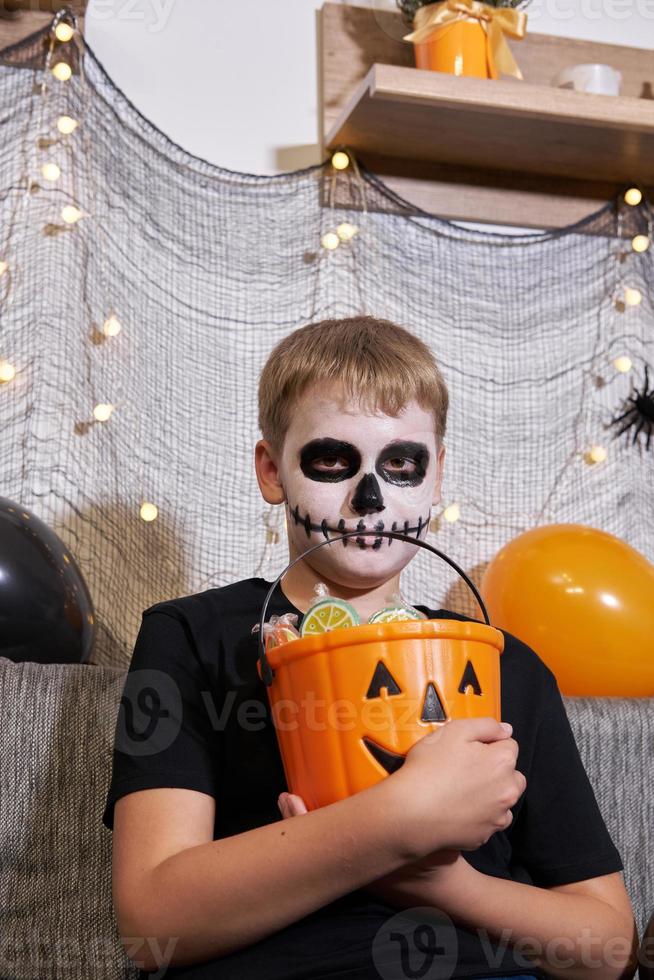 The child takes out the candy from the bucket for Halloween photo