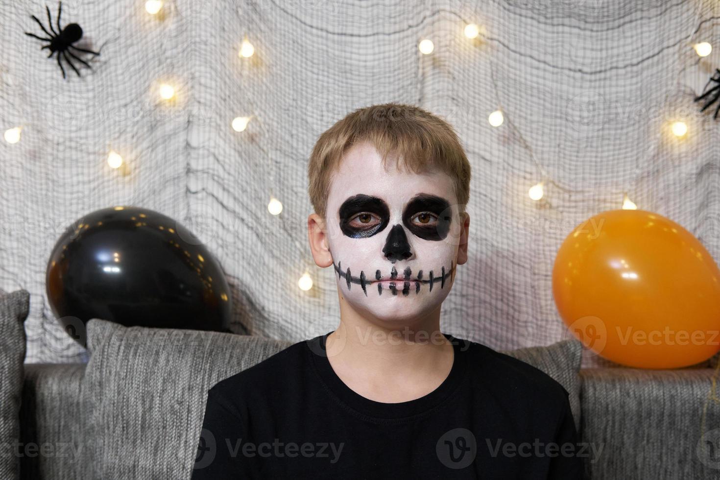 Portrait of a boy with makeup on his face in the form of skeleton for Halloween photo