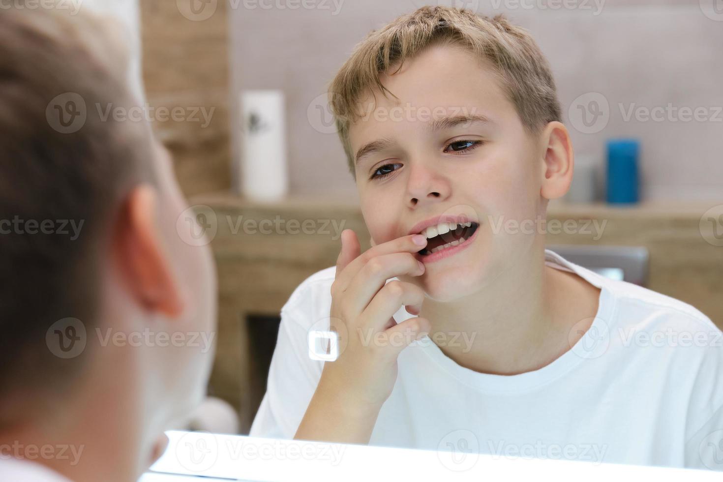 Reflection in the mirror of a schoolboy looking at his teeth. photo