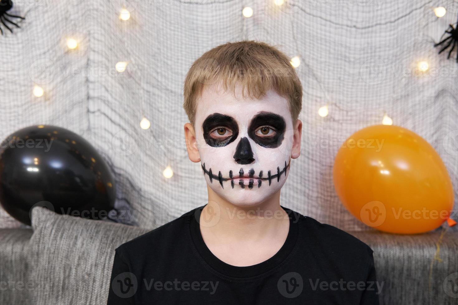 Portrait of a boy with makeup on his face in the form of skeleton for Halloween photo