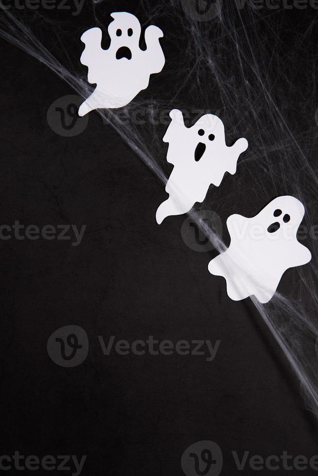 Halloween Decoration and horror concept - spider web with ghosts over black background photo