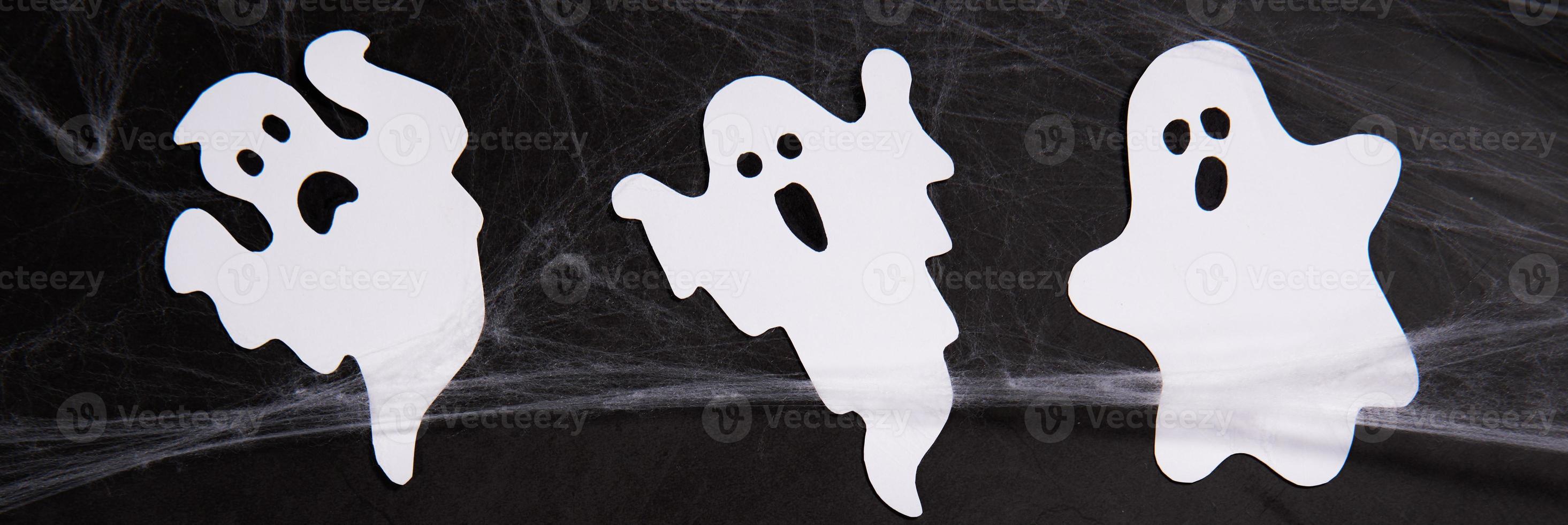 Halloween flat lay composition with spider web and ghosts on black background. photo