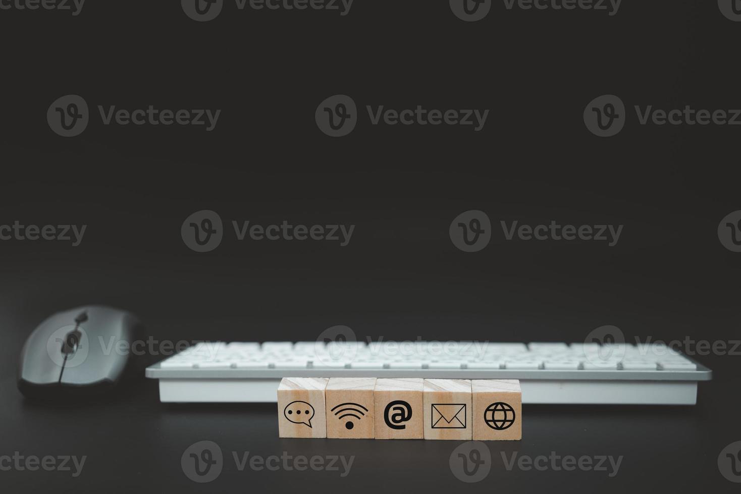 Online business communication symbols contact us or e-mail address marketing concept on wooden cubes with computer keyboard background. photo