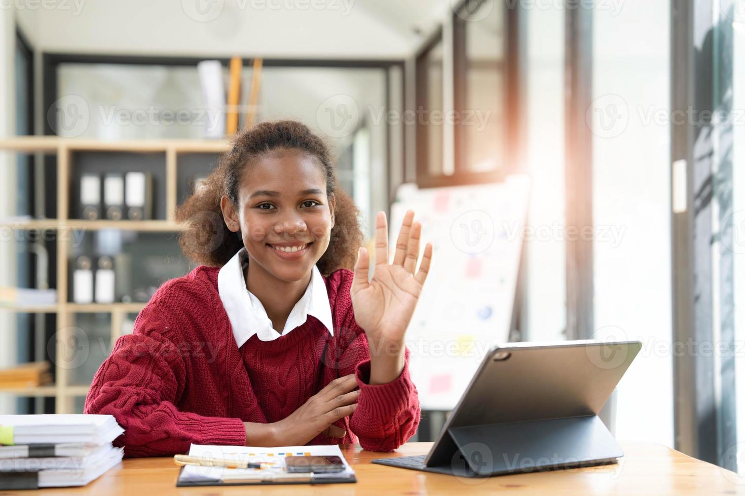 Young happy woman of African American ethnicity wear casual clothes use laptop waving hand sit in armchair stay at home flat rest relax spend free spare time in living room photo