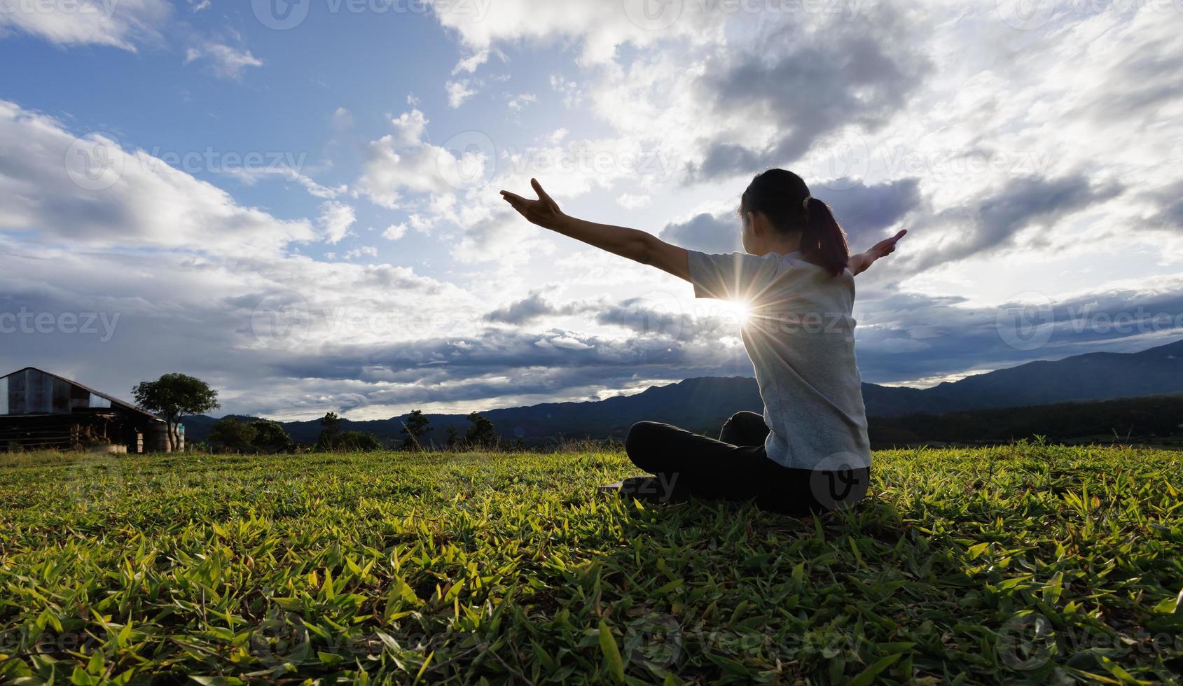 mujer orando por gracias a dios orando con las manos juntas para pensar en un dios amoroso, alabamos a dios con un destello de luz en la naturaleza verde. foto