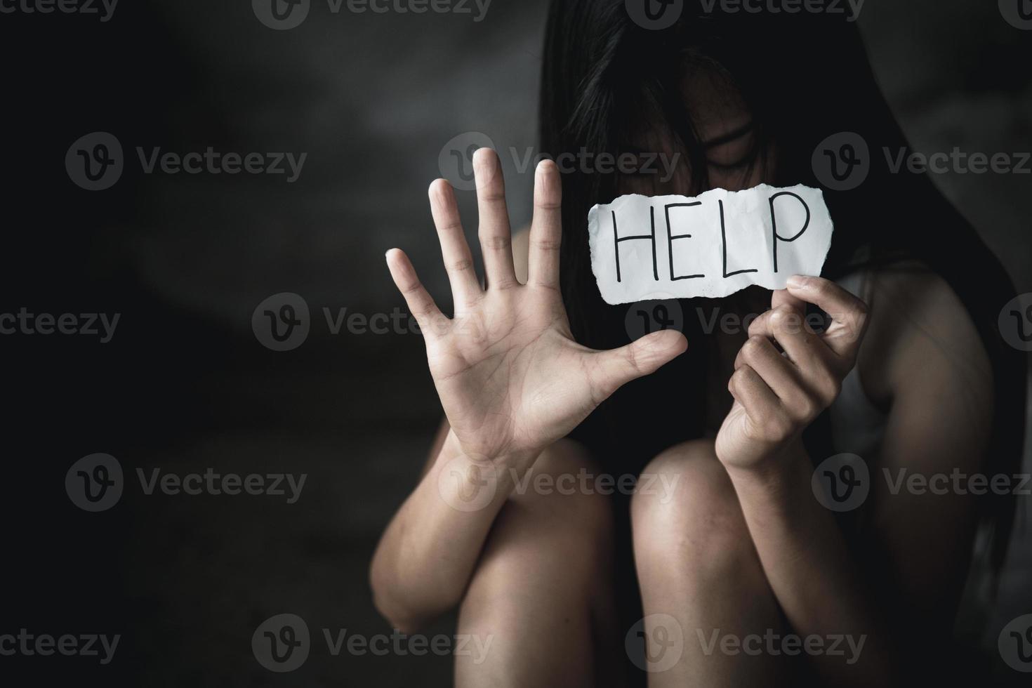 mujeres sentadas solas con expresión deprimida y mostrando un papel con un texto de ayuda. detener la violencia contra las mujeres. foto