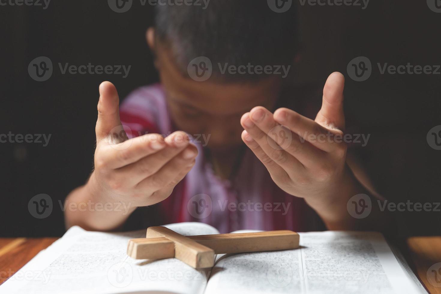 Soft focus on a Religious Christian Child  praying over Bible indoors, Religious concepts. prayer to god. photo