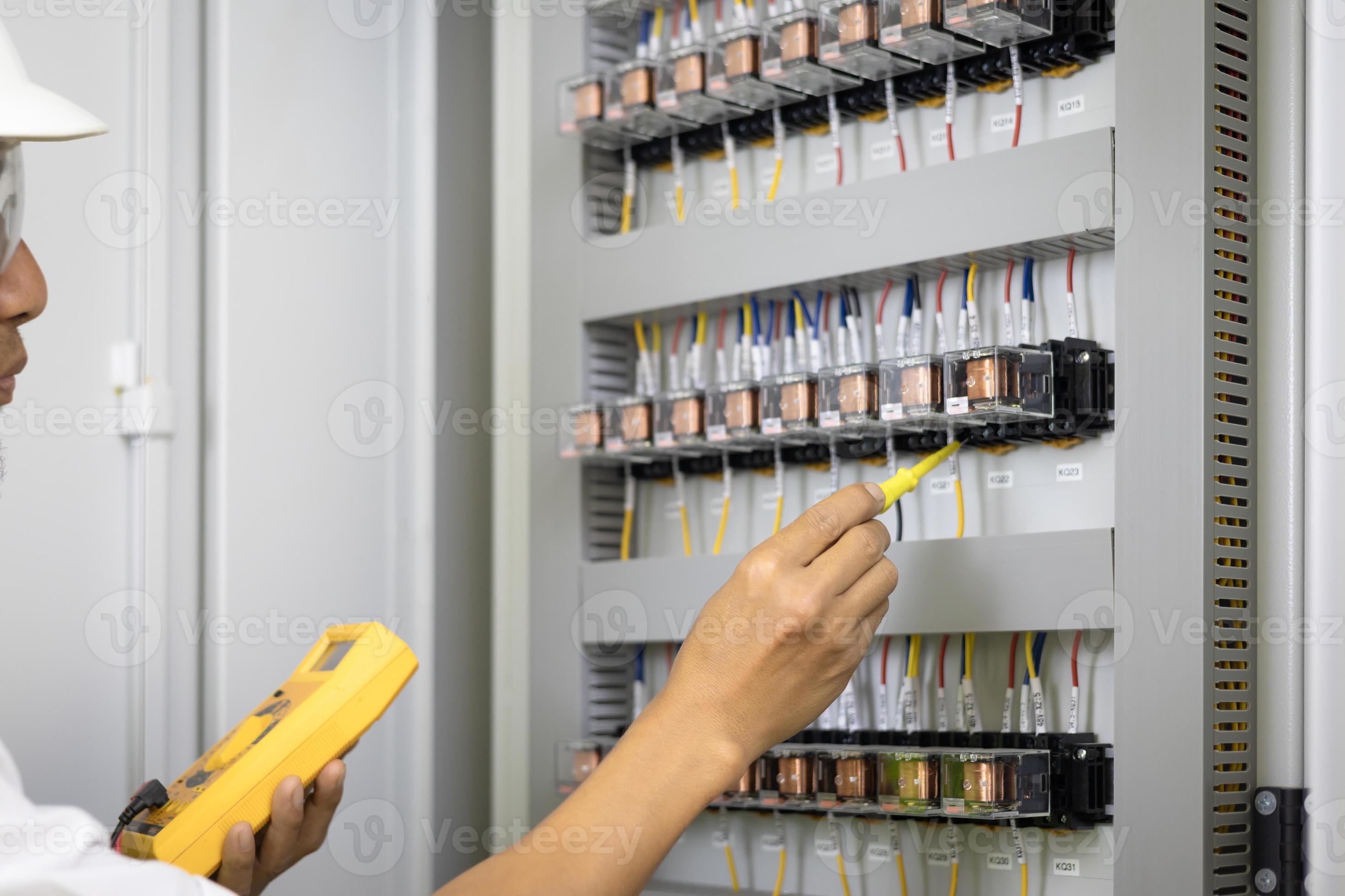 A male electrician works in a switchboard, Electrical terminal box