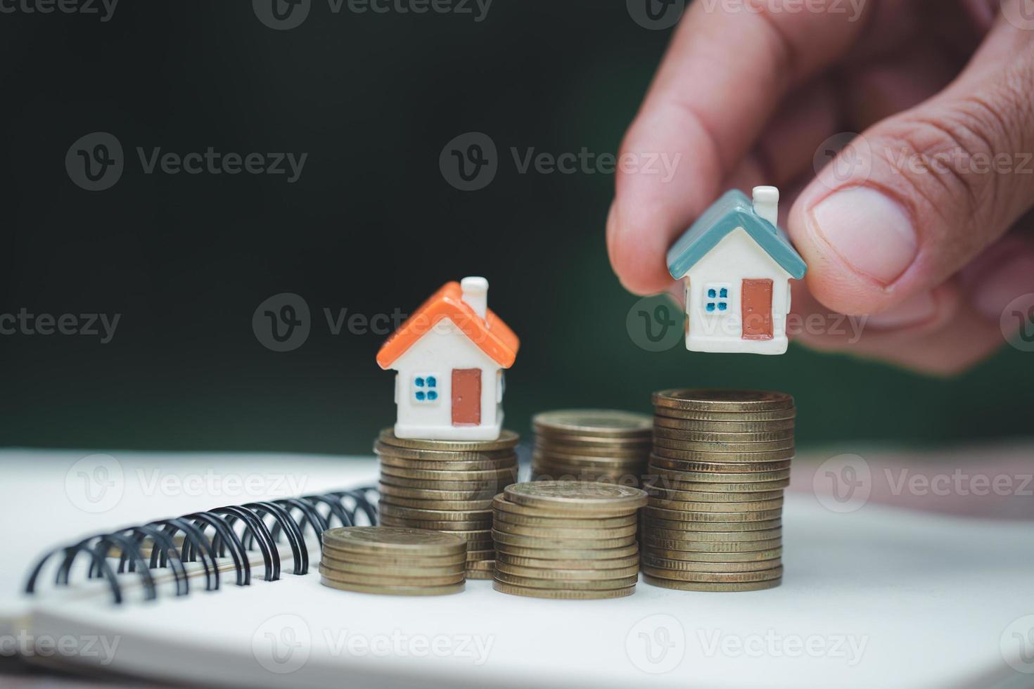 A woman holding a house on a pile of coins is planning savings money. concept for property ladder, mortgage and real estate investment. for saving or investment for a house. photo