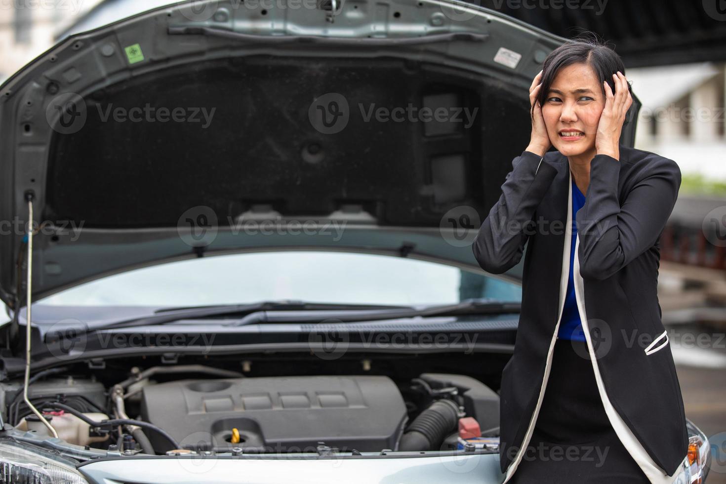 A businesswoman checks a broken car on the side of the road and she is stressed that her car is broken. photo