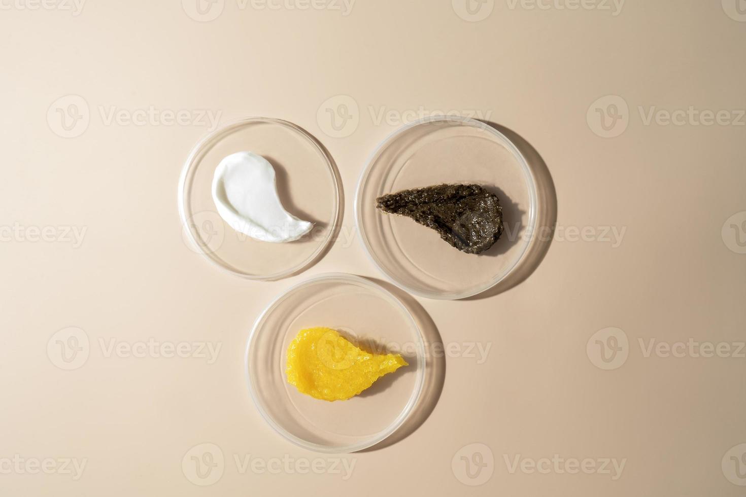 Three cosmetic smudges of body scrub and cream lying on plates on a beige background photo