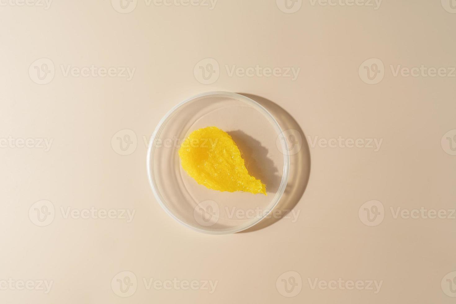 A yellow smudge of a mango body scrub  lying on a plate on a beige background photo