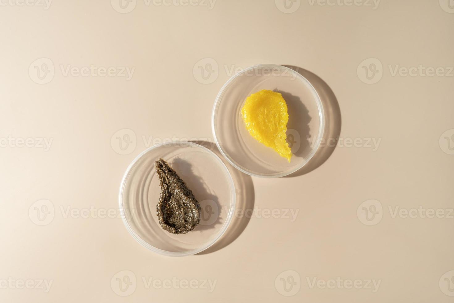 Two cosmetic smudges of body scrub and cream lying on plates on a beige background photo