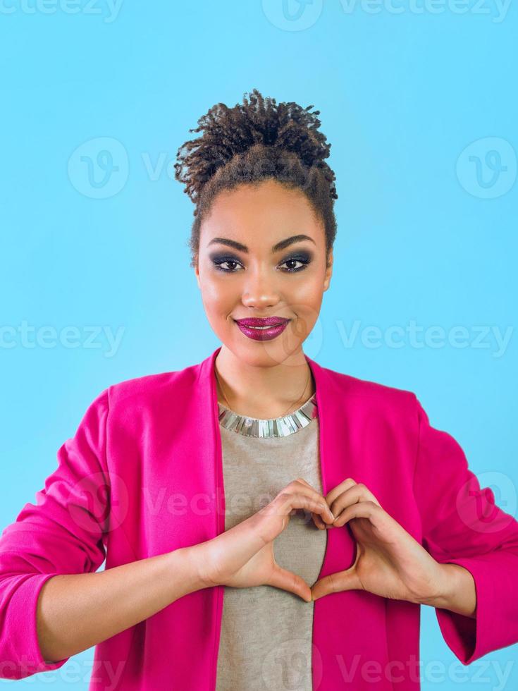 bella y atractiva joven sonriente sosteniendo sus manos como corazón y mostrando su amor. amor, apoyo, unión, cuidado, concepto de diversidad foto